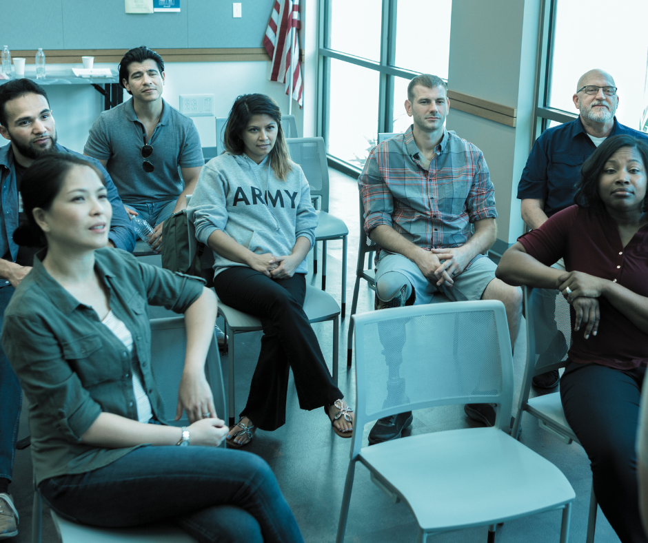 A diverse group of African American, South Asian, Asian, Native American, and other military community members in a support setting